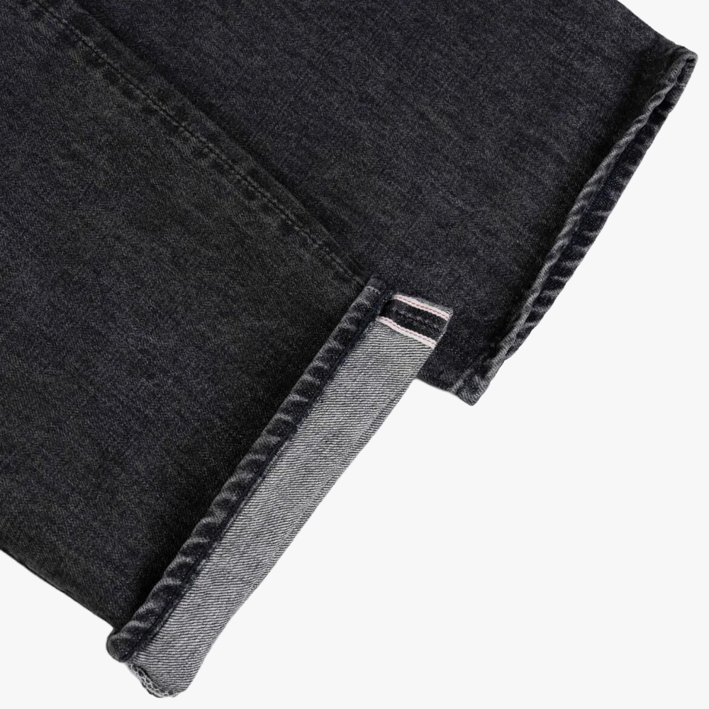 Close-up of the black garment-washed denim showing weave texture, subtle fading, and soft washed character.