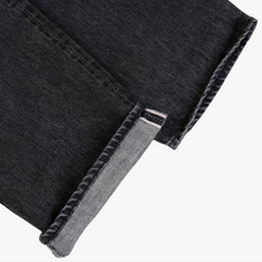 Close-up of the black garment-washed denim showing weave texture, subtle fading, and soft washed character.