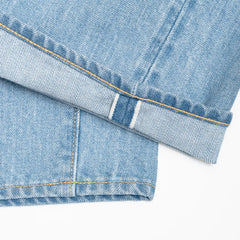 Close-up of the denim fabric showing light wash, fading, and distressed details.