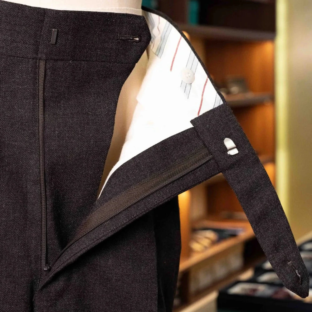 Close-up of the waistband and button area showing stitching, hardware, and precise tailoring.