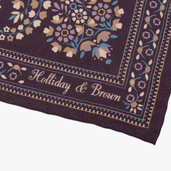 Close-up of the Holliday & Brown plum pocket square corner highlighting the printed border, detailed motifs, and brand logo.