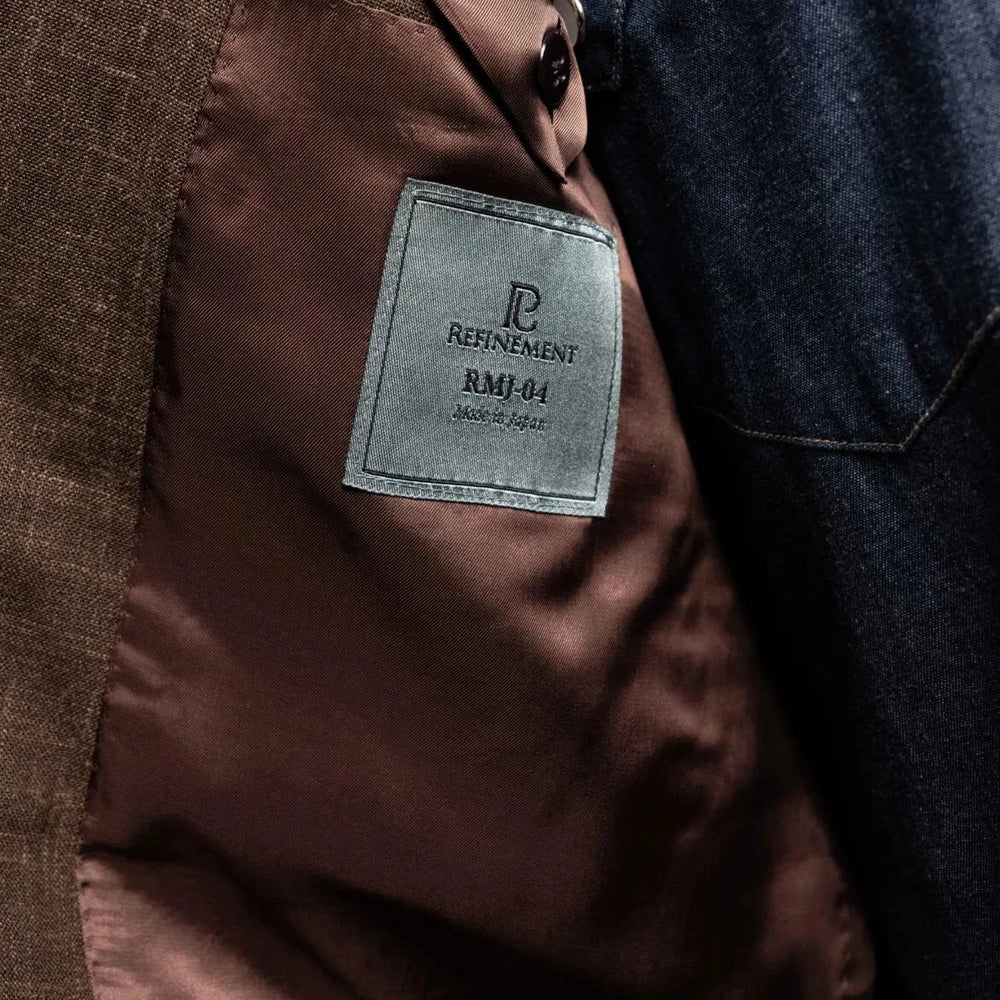 Close-up of the interior label on the RMJ-04 Dark Brown Jacket showing Refinement Made By Ring Jacket branding and lining construction.