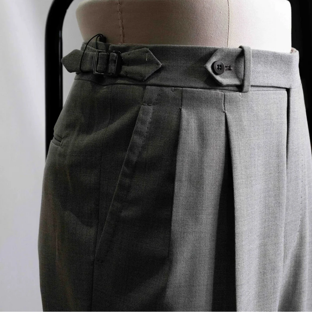 Close-up of the waistband showing button closure, belt loops, stitching precision, and sartorial construction.