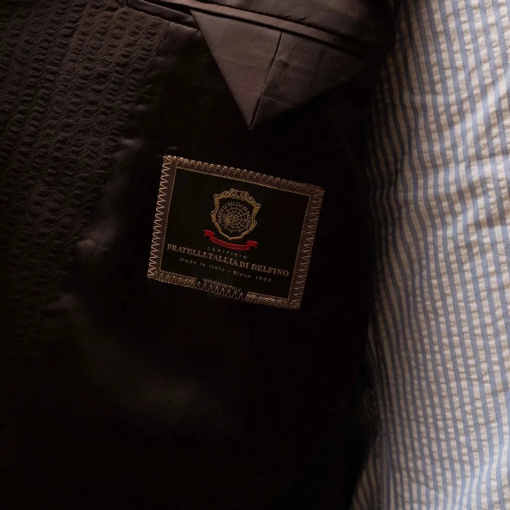 Close-up of the inside label showing Refinement Tailoring branding and Tallia di Delfino cloth tag.