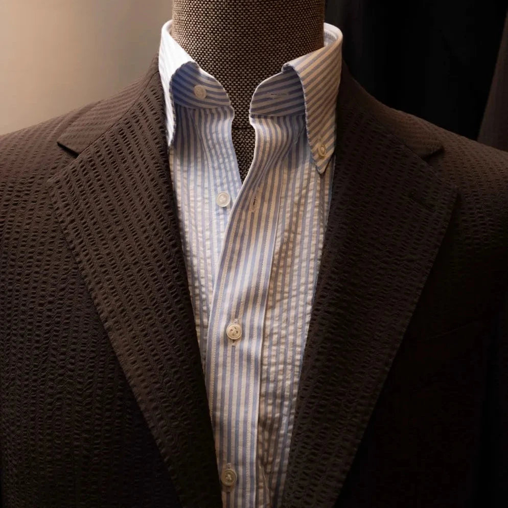 Close-up of the notch lapel showing pick stitching and the distinctive seersucker puckering from Tallia di Delfino.