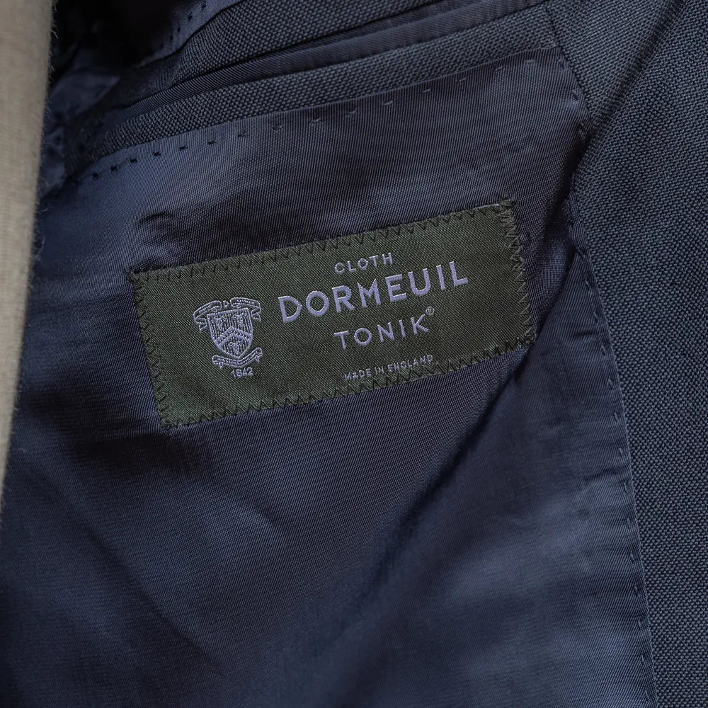 Close-up of the interior labels of the RMJ-03 Navy Suit by Dormeuil showing Refinement × Ring Jacket branding and Dormeuil fabric label.
