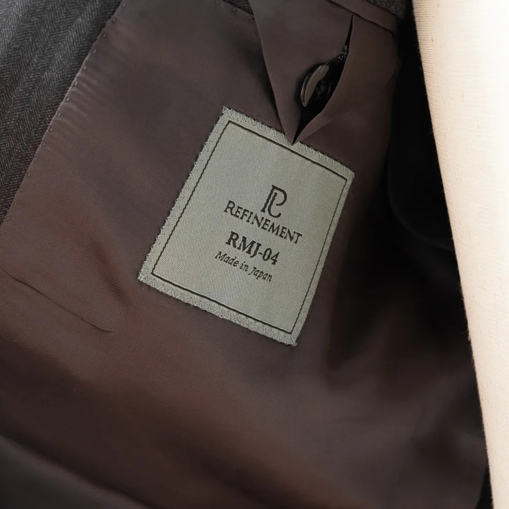 Close-up of the interior labels of the RMJ-04 Suit showing Refinement × Ring Jacket branding and Vitale Barberis Canonico fabric label.