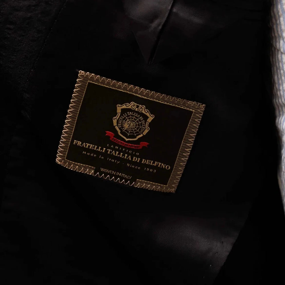 Close-up of the interior label showing Refinement Tailoring branding and Tallia di Delfino cloth identification.