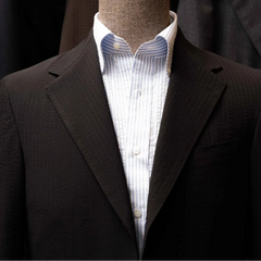 Close-up of the notch lapel showing pick stitching and the distinctive puckered black seersucker weave from Tallia di Delfino.