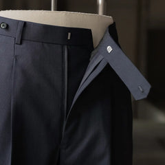 Detail of the trousers’ front closure showing the waistband, extension tab, and interior finishing.