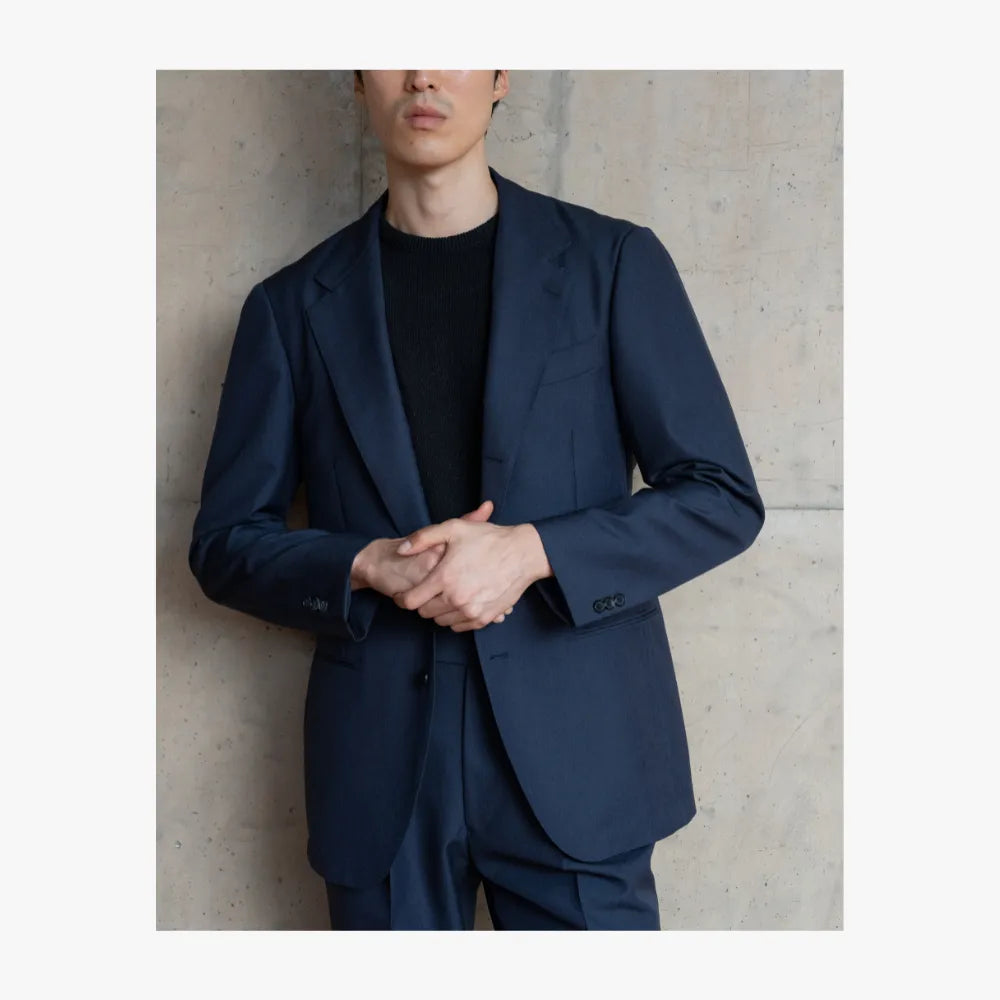 Man wearing RMJ-03 navy single breasted suit by Ring Jacket made with Doemueil fabric, styled in a refined tailored look
