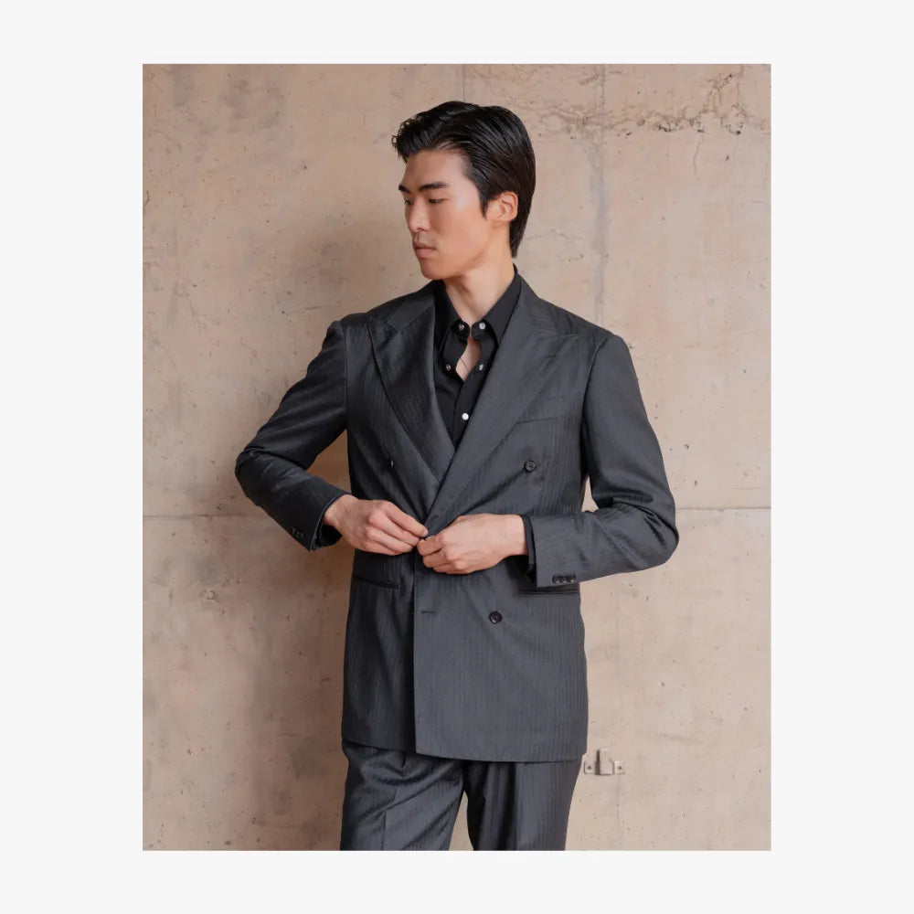 Man wearing RMJ-04 charcoal grey double-breasted suit by Ring Jacket, styled in a refined tailored look