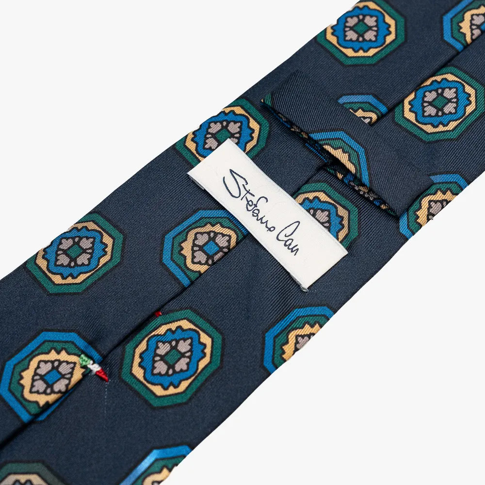 Close-up of the back side of the Stefano Cau floral tie showing the brand label, hand-finished stitching, and clean construction.