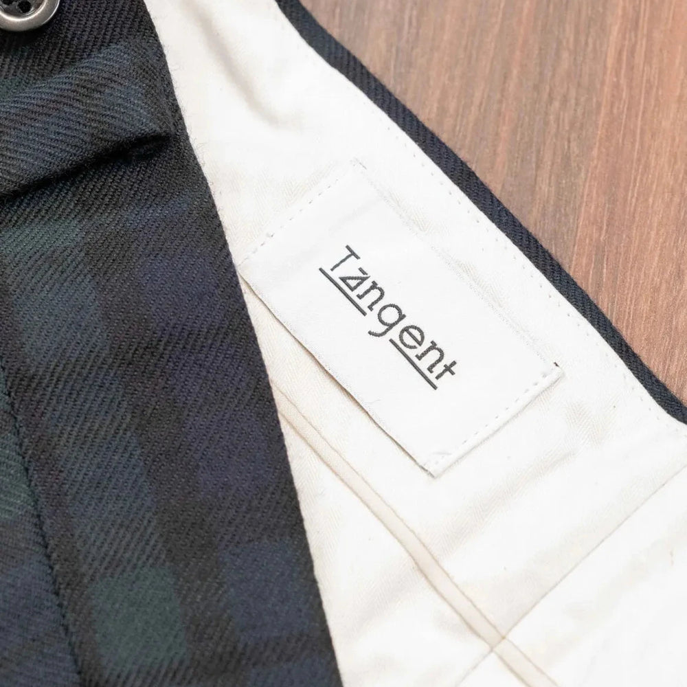 Close-up of the inner label of the Tangent Tan 25° Wool Check Black Watch trousers showcasing branding and craftsmanship.