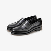 A pair of TLB Mallorca 718 Queens Penny Loafers in black box calf leather, shown at an angle to highlight the elegant silhouette and polished finish.