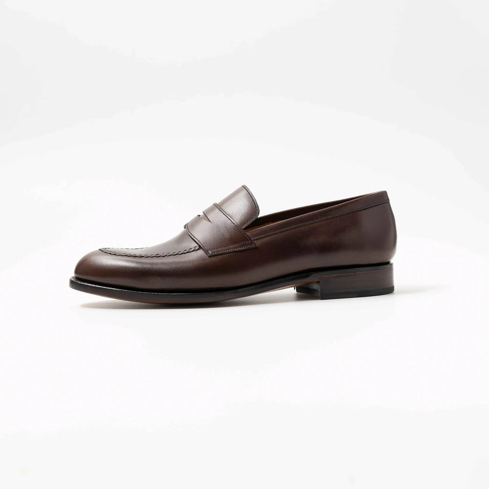 Side view of TLB Mallorca 315 Jones Penny Loafer Dark Brown Vegano a single dark brown leather penny loafer with a sleek silhouette and leather sole .
