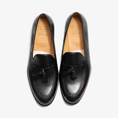 Pair of black loafers with tassels on a white background