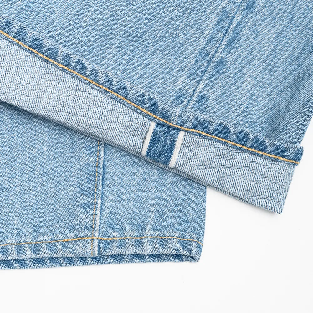 Close-up of the denim fabric showing light wash, fading, and distressed details.