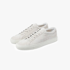 Full view of the Common Projects Achilles Premium in suede 2573 in light grey featuring a minimalist low-top silhouette and soft suede texture.