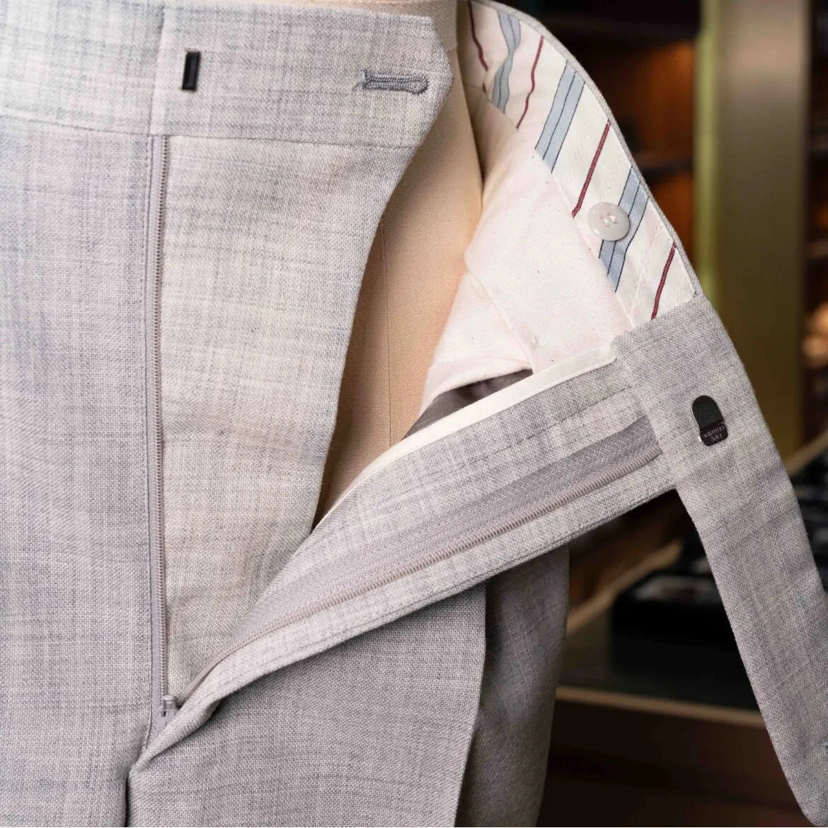 Close-up of the waistband and button area on the Drummers Trousers Light Grey showing stitching, hardware, and construction details.