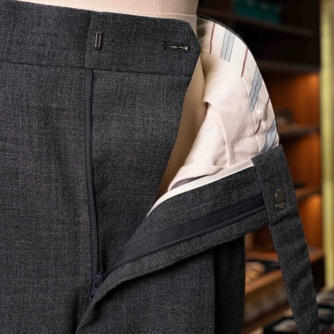 Close-up of the waistband and button area showing hardware, stitching, and precise construction.