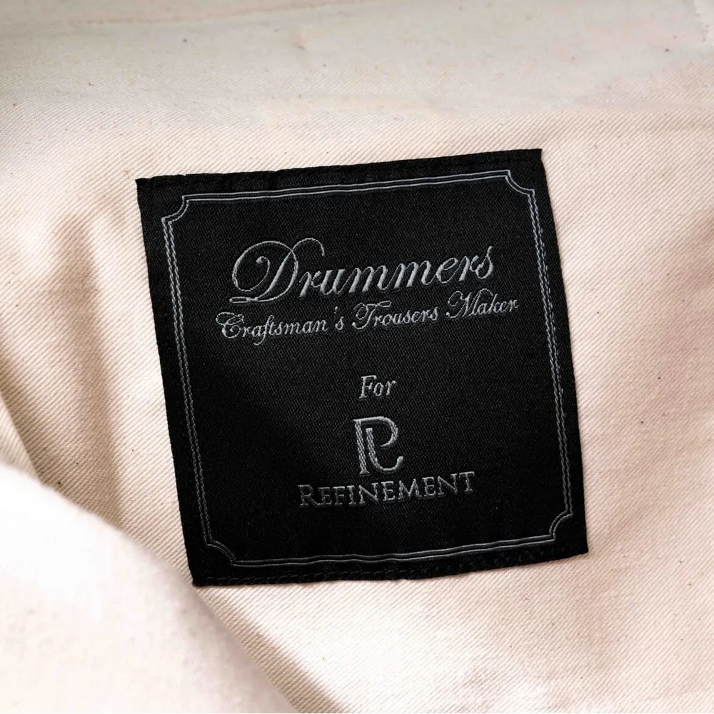 Close-up of the internal label on the Drummers Trousers Mid Grey showing branding and inner construction.