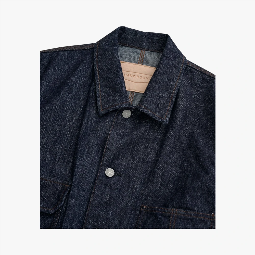 Close-up of the spread collar showing stitching precision and denim texture.