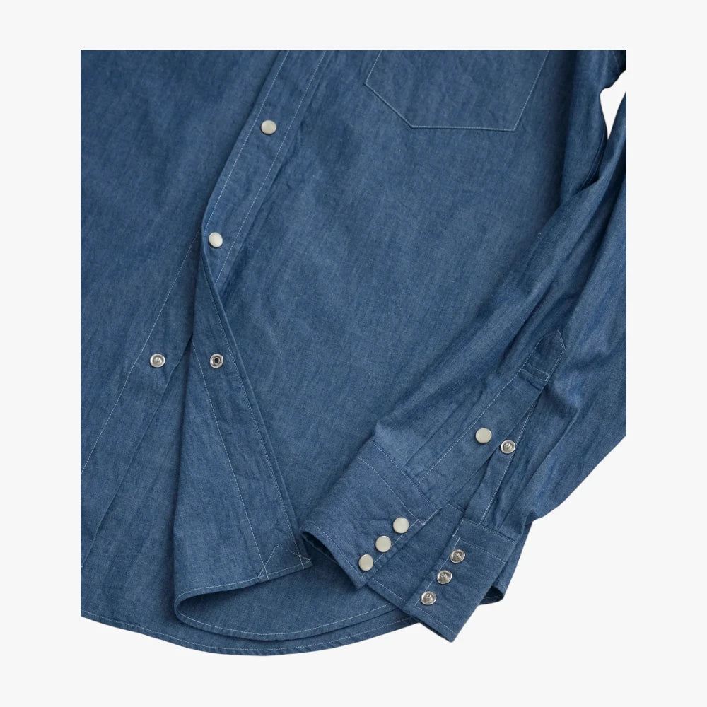 Close-up of the snap-button cuff showing finishing, stitching, and chambray grain.