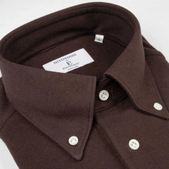 Close-up of the button-down collar showing roll shape, stitching precision, and refined textured knit in dark brown.