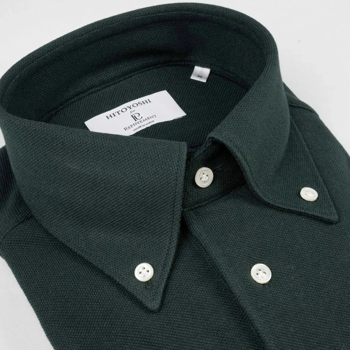 Close-up of the button-down collar showing the collar roll, stitching precision, and knit texture.