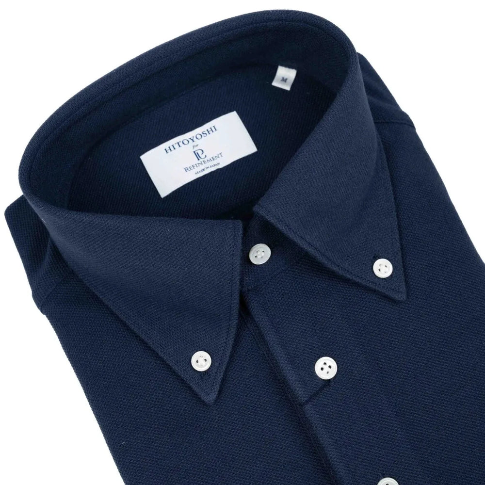 Close-up of the button-down collar showing roll shape, stitching precision, and refined knit texture.