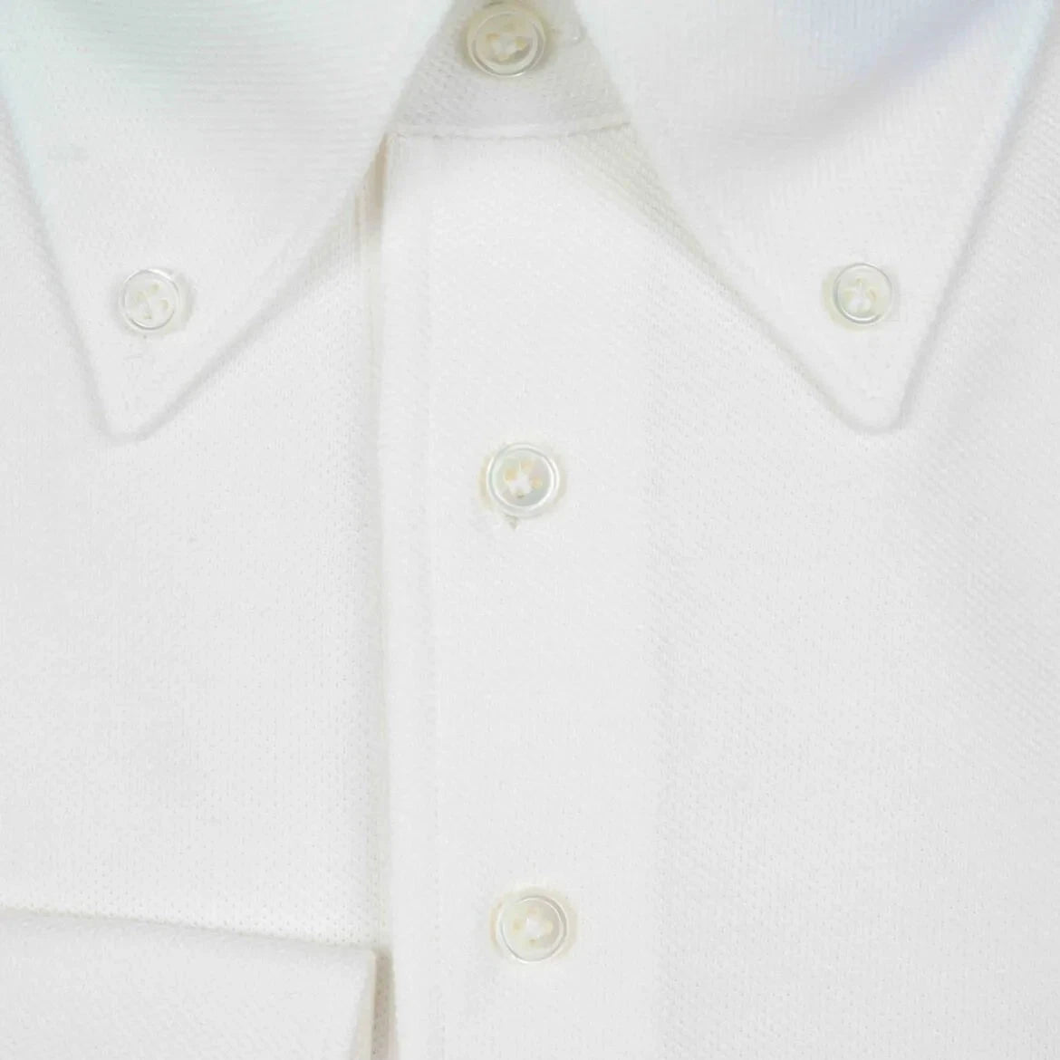 Close-up of the placket showing button placement, knit density, and precise finishing.