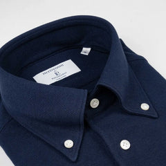Close-up of the button-down collar showing roll shape, stitching precision, and refined knit texture.
