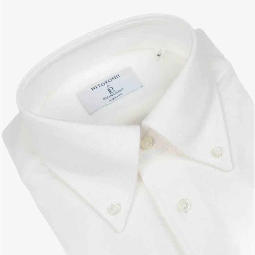 Close-up of the button-down collar showing the collar roll, stitching precision, and knit structure.
