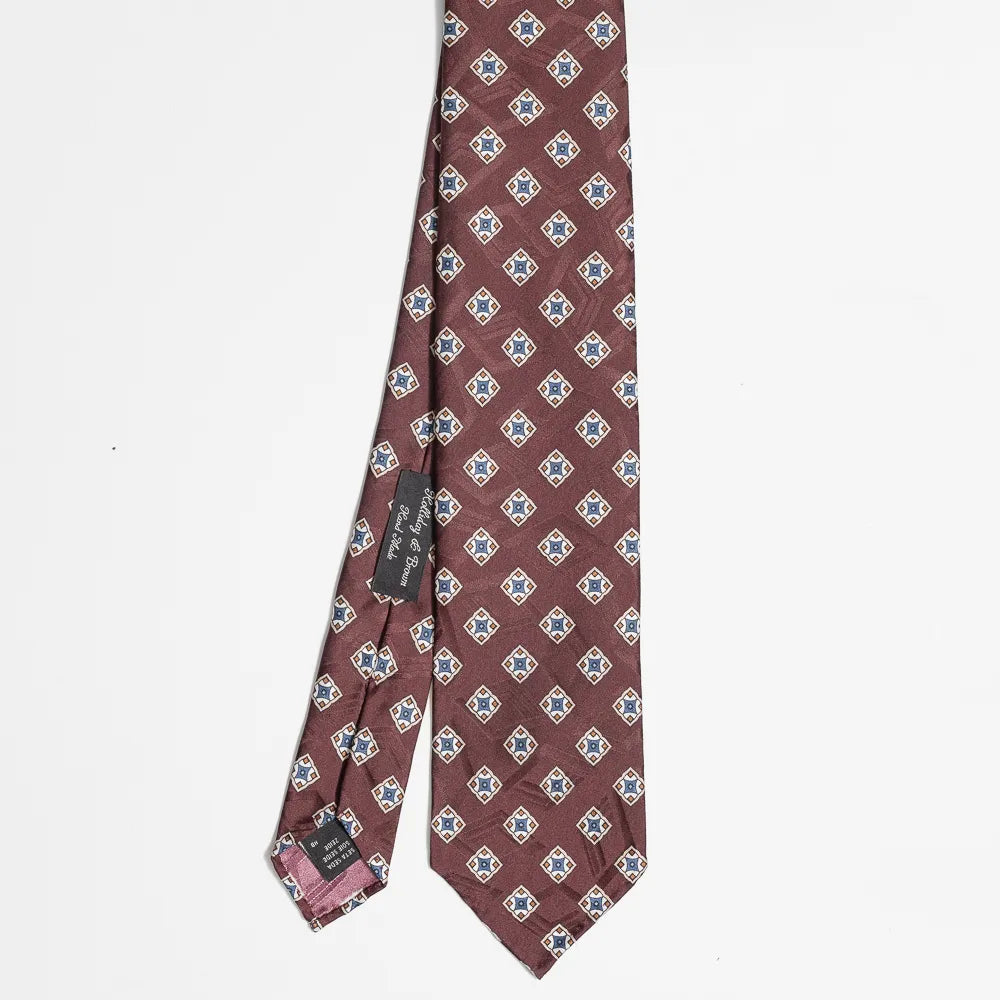 Full view of the Holliday & Brown geometric tie in burgundy showing structured pattern and refined proportions.