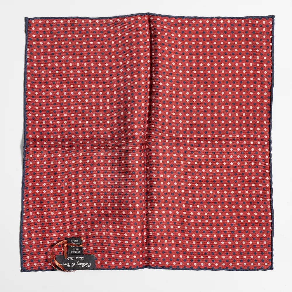 Close-up of the red dot pattern highlighting silk texture and precise weaving detail.