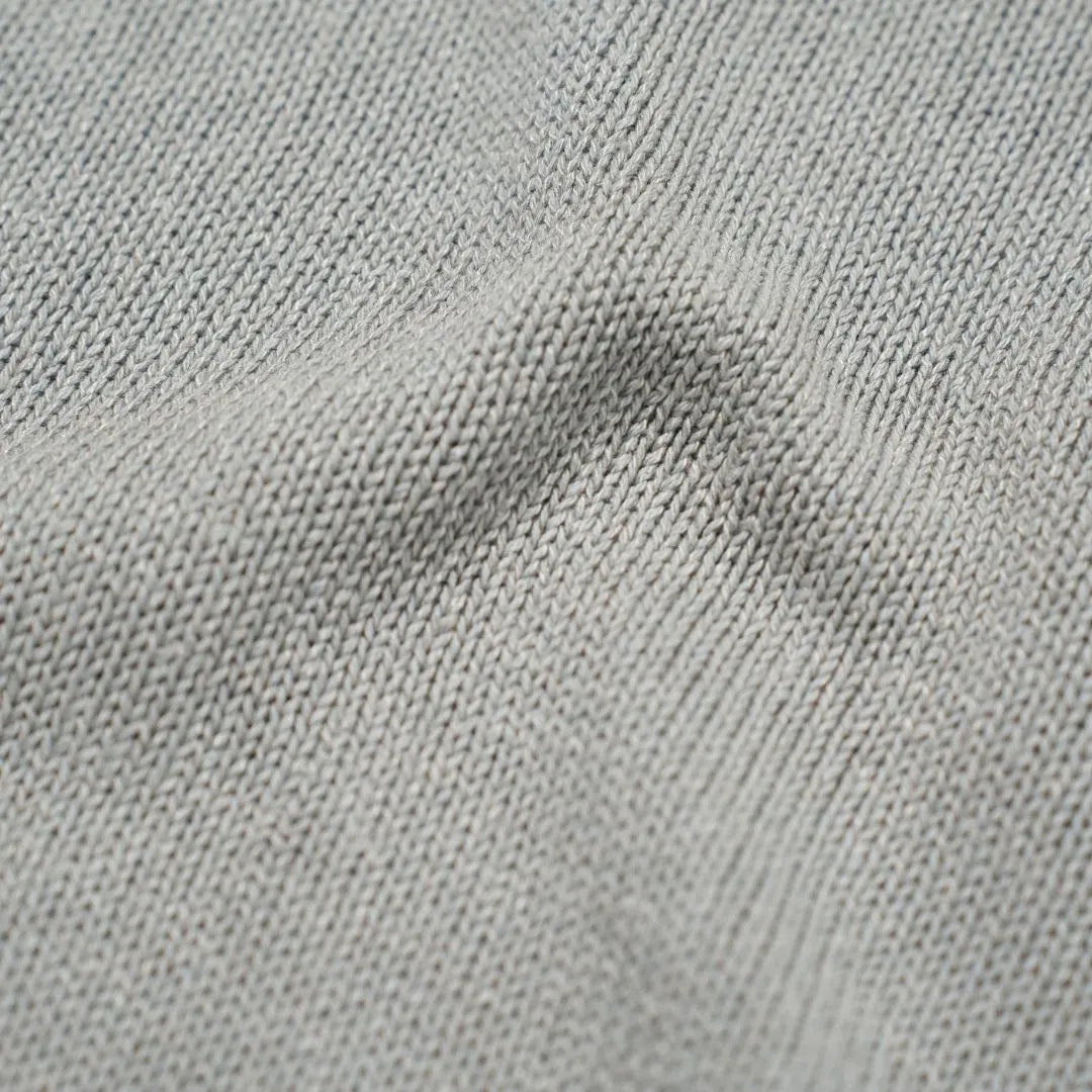 Close-up of the paper-silk blend fabric showing its ultra-light texture, subtle sheen, and soft light grey coloration.