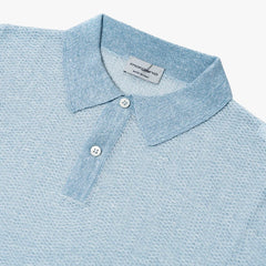 Close-up of the collar and button placket showing knit texture, contrast color detail, and refined finishing.