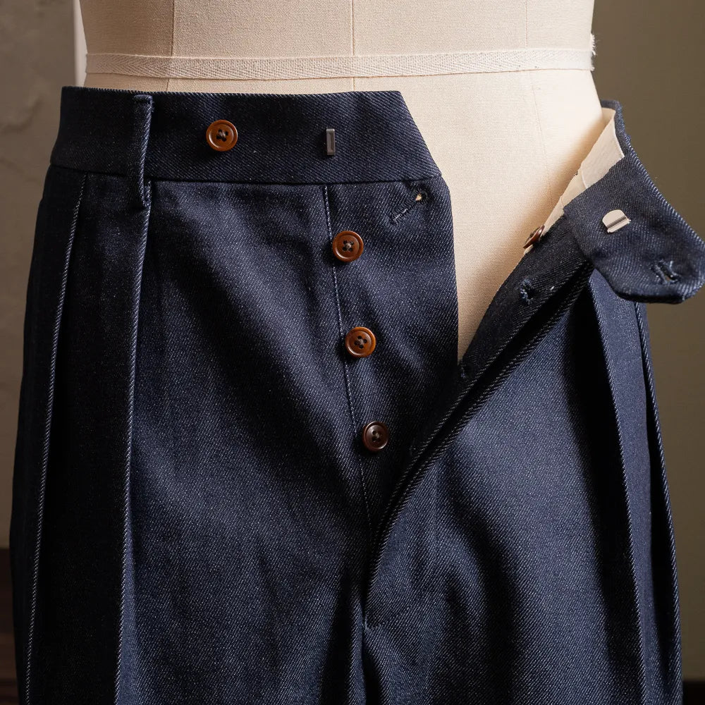 Close-up of the front fly and button fastening showing denim texture and refined construction.
