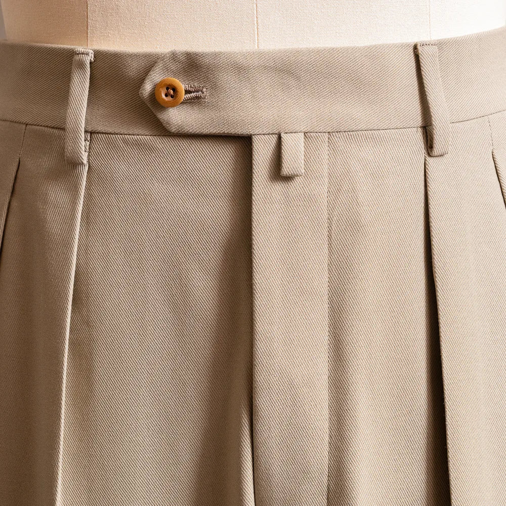 Close-up of the waistband and front pleats highlighting tailored structure and stitching detail.
