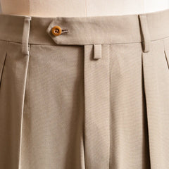 Close-up of the waistband and front pleats highlighting tailored structure and stitching detail.
