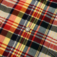 Close-up of the red–yellow checked Madras fabric showing handwoven texture, color variation, and breathable cotton weave.