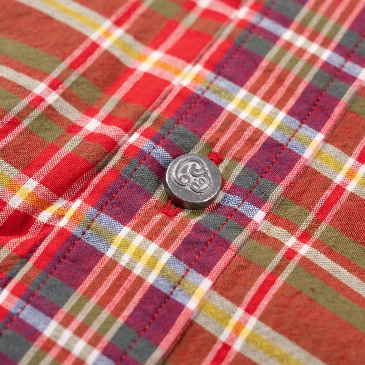 Close-up of the red Madras fabric showing handwoven texture, color variation, and lightweight cotton weave.