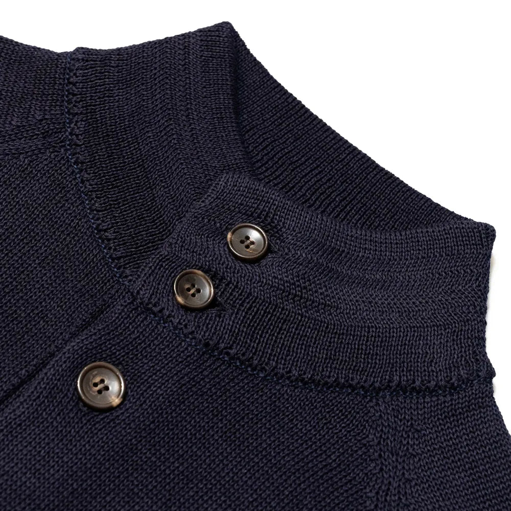 Close-up of the knit bomber collar showing rib-knit structure, button placement, and refined navy yarn texture.