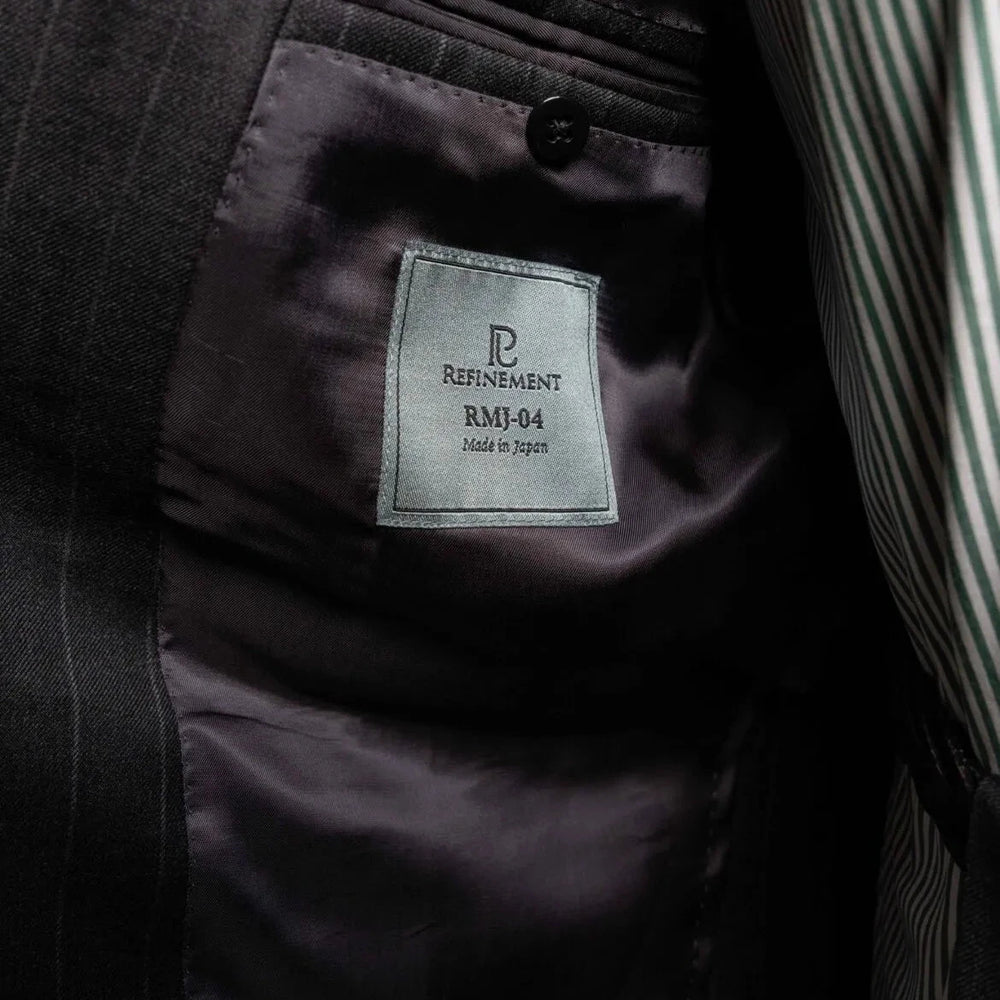 Close-up of the interior labels on the RMJ-04 Chalk Stripe Charcoal Grey Suit showing Refinement Made By Ring Jacket branding and Ermenegildo Zegna Electa fabric label.