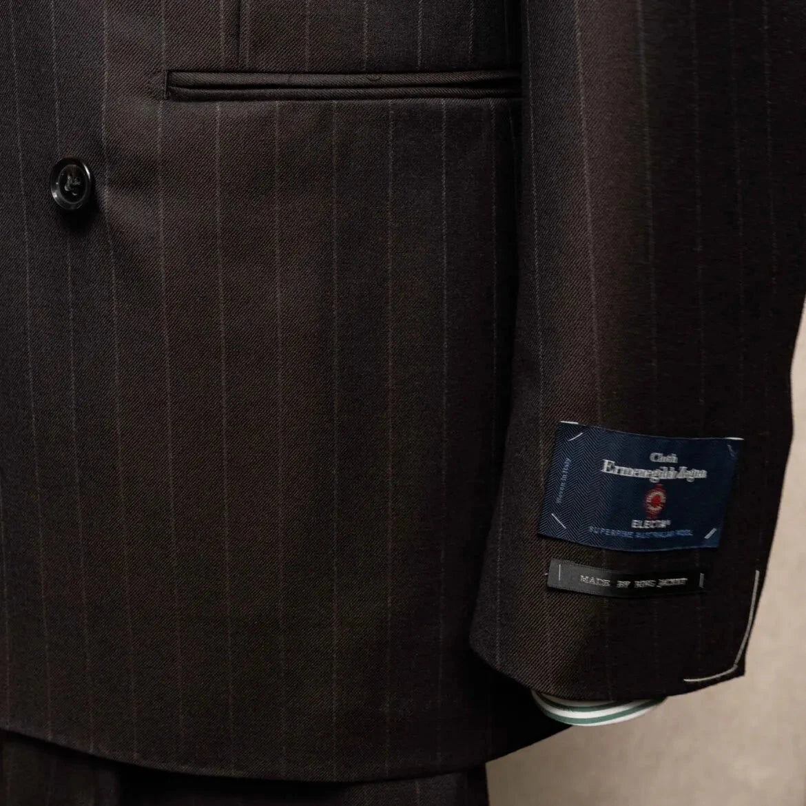 Close-up of the sleeve and hem area showing sleeve buttons, stitching, and clean finishing on the RMJ-04 Chalk Stripe Dark Brown Jacket.