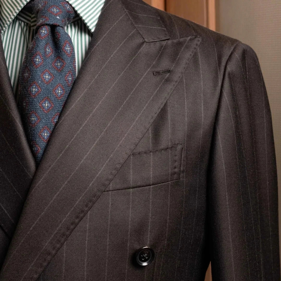 Close-up of the peak lapel on the RMJ-04 Chalk Stripe Dark Brown Jacket showing the lapel roll, sharp peak structure, and luxurious Zegna Electa wool texture