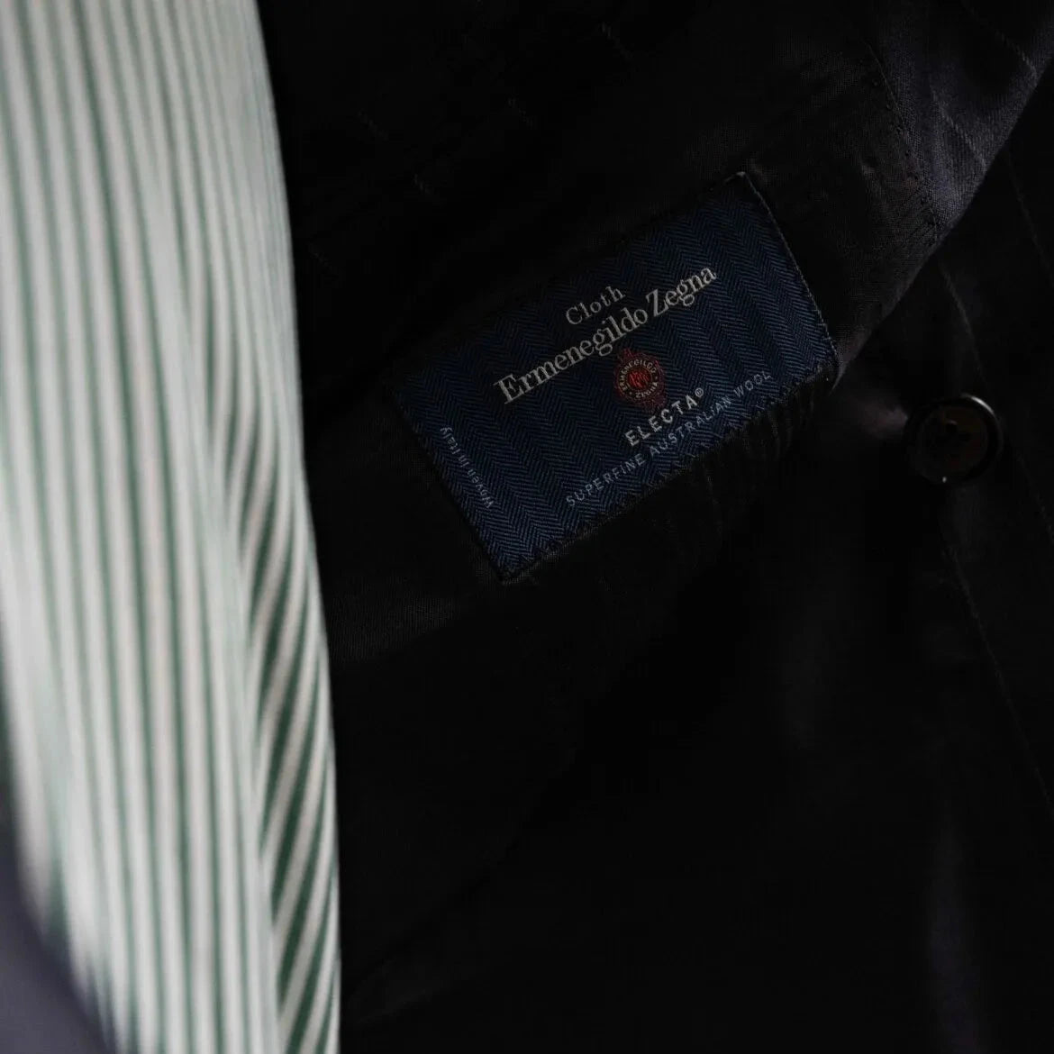 Close-up of the interior labels on the RMJ-04 Chalk Stripe Navy Suit showing Refinement Made By Ring Jacket branding and Ermenegildo Zegna Electa fabric label.
