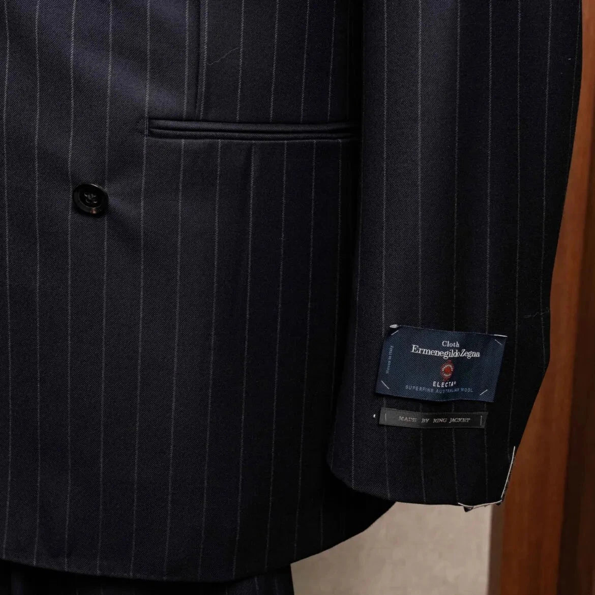 Close-up of the sleeve and hem area showing sleeve buttonwork, stitching, and clean finishing on the RMJ-04 Chalk Stripe Navy Jacket.