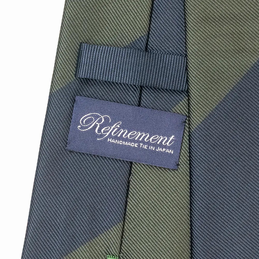 Close-up of the Refinement block stripe neck tie showing textured silk weave and brand label detail.

